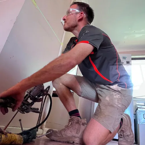 Buildfix technicians injecting GeoPoly™ resin beneath indoor concrete slab to fill voids and lift the floor