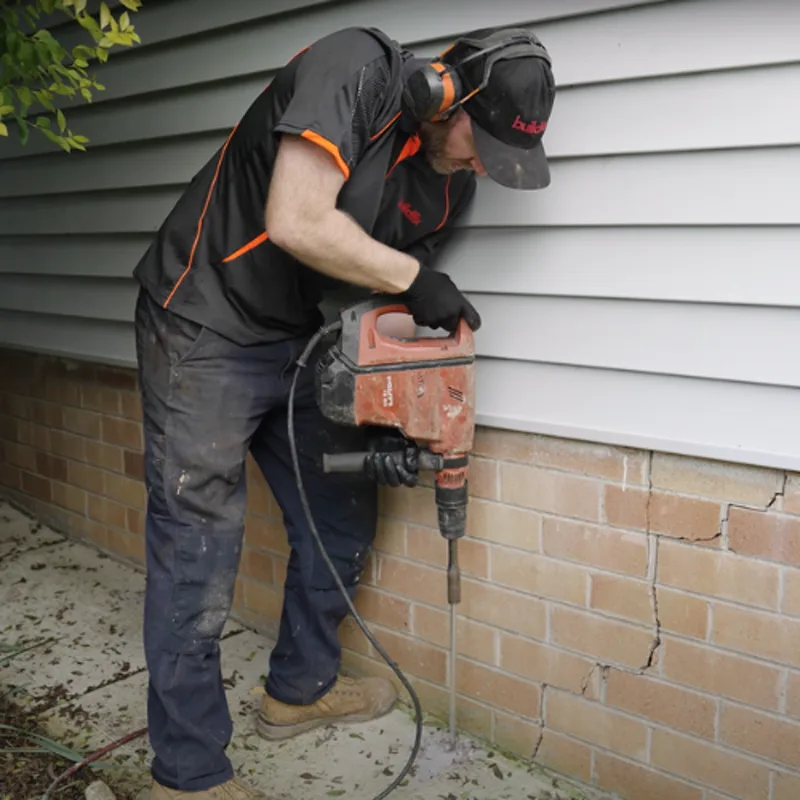 Buildfix technician drilling small coin-sized access holes for GeoPoly™ injection