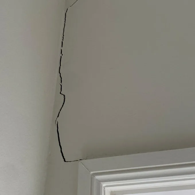 Crack running diagonally from corner of window frame through plaster
