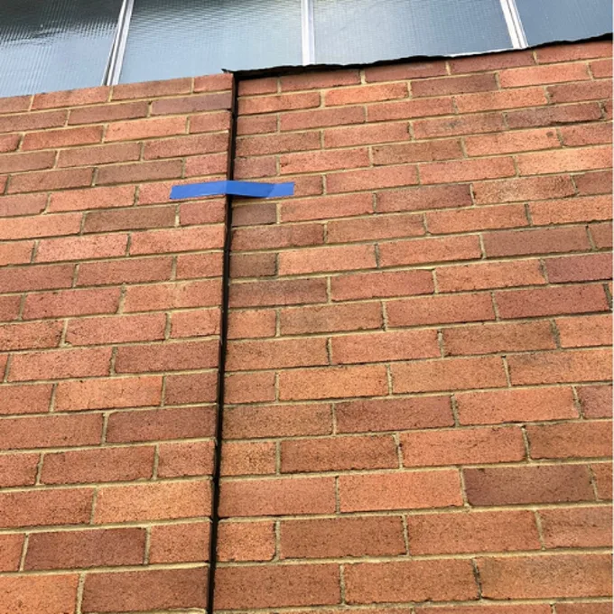 Brick wall leaning outward with vertical crack due to uneven foundation settlement