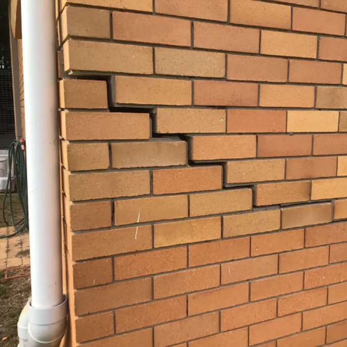 Stepped crack following mortar joints in brick wall caused by foundation subsidence